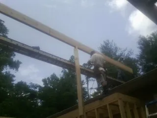 Carpenter setting a ridge beam over a new addition frame — Ice Dam Removal by Roofing Brothers in Lumber Bridge
