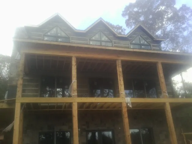 Dormers and porch framing on a large log home under construction — Roof Coating work by our crew in Lumber Bridge