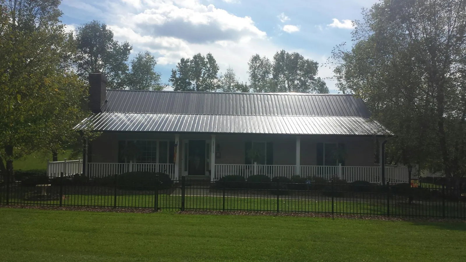Gray metal roof on a brick ranch with a full width front porch — Gutter Guard Installation work by our crew in Lumber Bridge