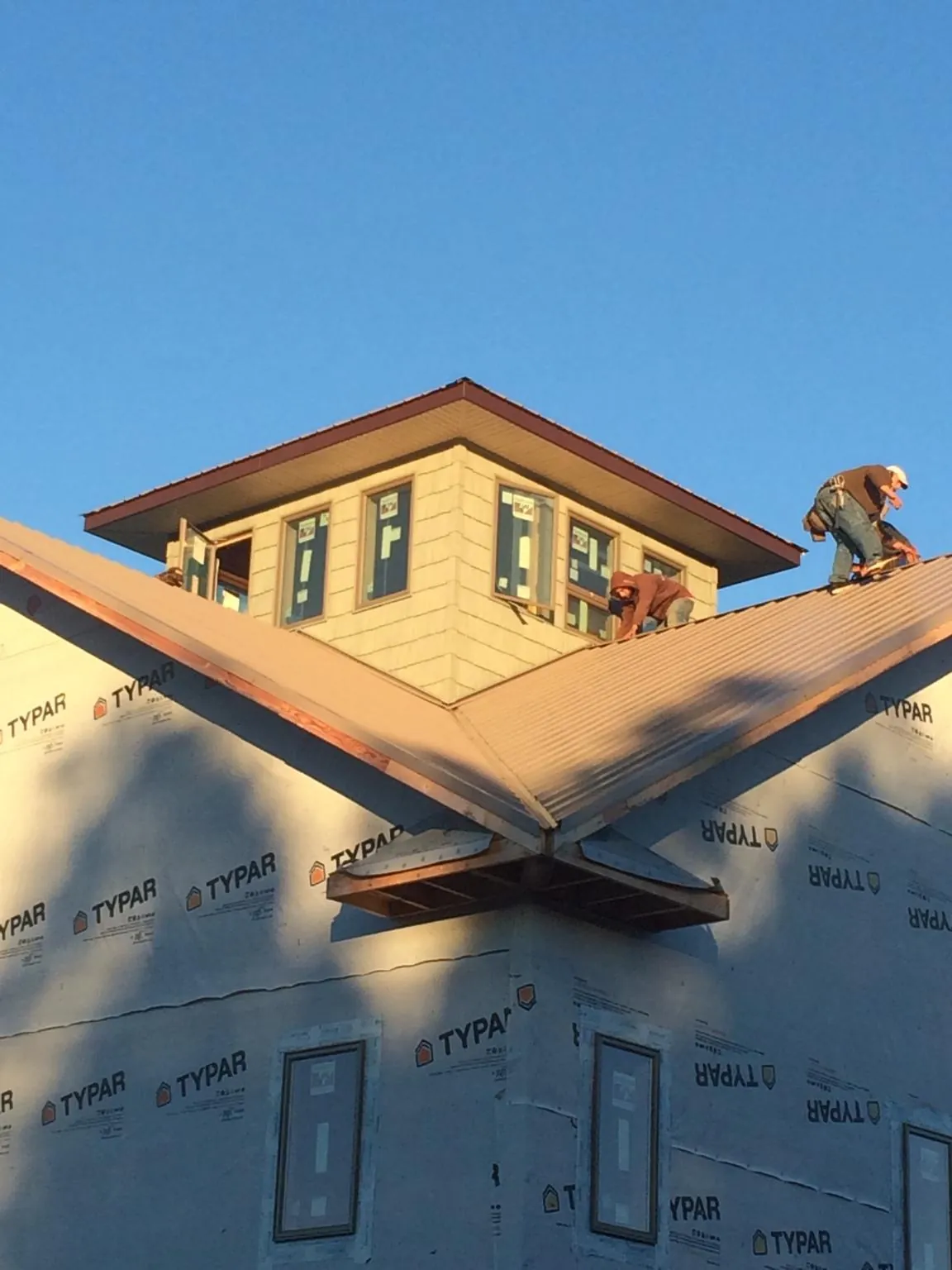 Roofers working around a rooftop cupola on a new metal roof at sunset — Roof Waterproofing in Lumber Bridge by Roofing Brothers